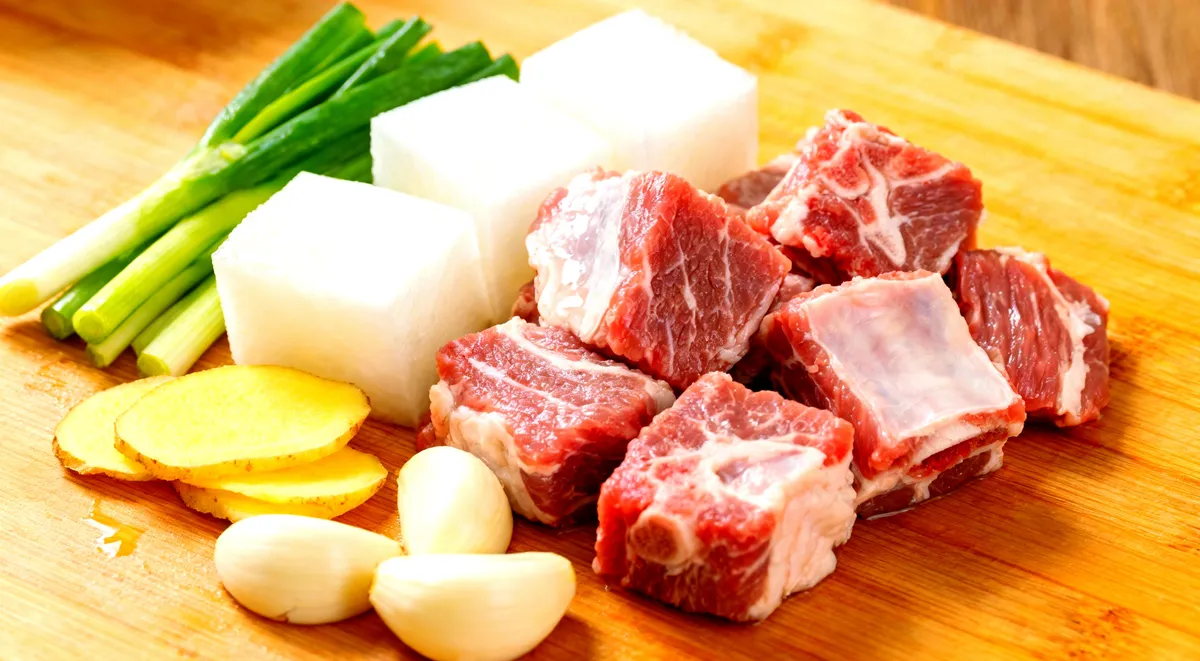 Ingredients for lamb and radish stew — raw lamb cubes, daikon radish, ginger, spices and sauces laid out