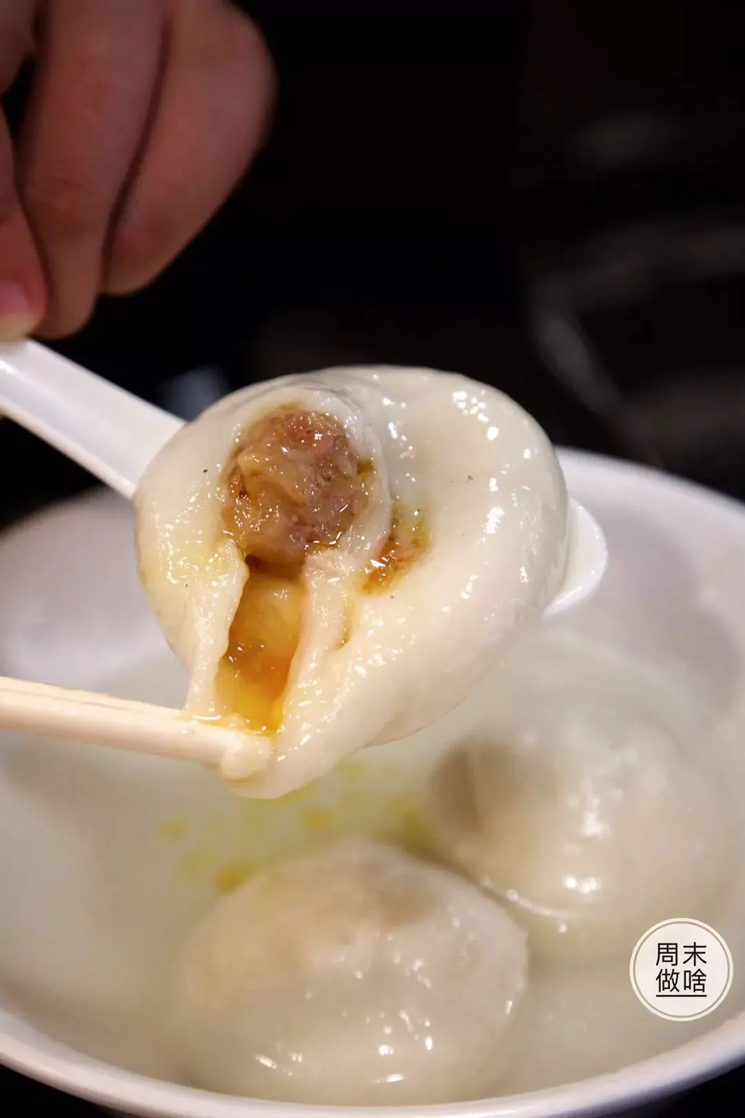 Tang yuan broken open to show the black sesame filling inside the soft glutinous rice shell